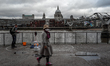 A man blows bubbles as people walk by, outside the Tate Modern gallery, in the south bank...