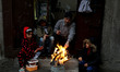 Members of a Palestinian family sit around a fire during heavy rain at Shati refugee camp...