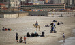 Palestinian families swim and palestinian youth jumps into the Mediterranean Sea as he enj...