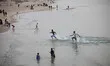 Palestinian families swim and palestinian youth jumps into the Mediterranean Sea as he enj...