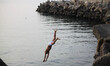 Palestinian families swim and palestinian youth jumps into the Mediterranean Sea as he enj...