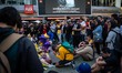 A man prays while on-lookers sit in silence looking at the flowers and candles at LA Live...