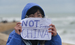 Taiwanese tourist carries a sign 'Not From China' during a walk Tel Aviv - Jaffa costline...