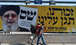 MThree young men pass by an election campaign posters for Shas religious political party,...