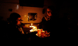A Palestinian woman holds tea inside their family's house during power cuts in Rafah refug...