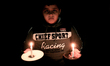 A Palestinian boy holds a candles at their family's house during a power cuts in Rafah ref...