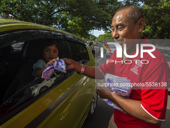 An administrator of the Indonesian-Chinese Association (INTI) distributed free masks to motorists on one of the roads in Palu, Central Sulaw...