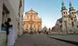 A street artist seats and looks at the empty street outside Saints Peter and Paul Church i...