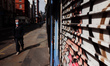 A man wearing mask walks past a shuttered accessories store on Berwick Street in Soho in L...