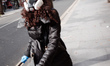 A woman wears a respirator mask and latex gloves on a near-deserted Tottenham Court Road i...