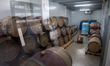 Wine bottles reflected on glass of wine warehouse, which uses for wine barrels fermentatio...