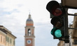 Traffic light with green light in the background the bell tower of the municipality of Rol...