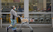 A woman wearing a face mask, pushes a shopping cart with her grocery items in Christchurch...