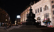 Two women sit on the steps of the Shaftesbury Memorial Fountain in a near-deserted Piccadi...