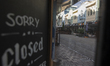 A closure sign is displayed on a shop in an empty street in Christchurch, New Zealand, on...