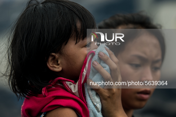 A woman covers a child's nose with a towel after a fire broke out in a slum area in Tondo, Manila in the Philippines on April 18, 2020. Abou...