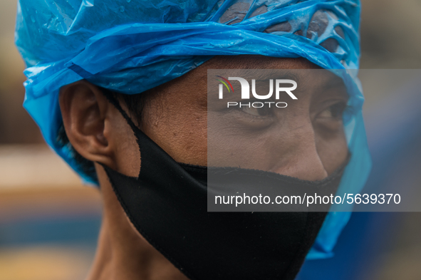 A man wearing a protective face mask covers his head with a plastic in a slum area in Tondo, Manila in the Philippines on April 18, 2020. Ab...