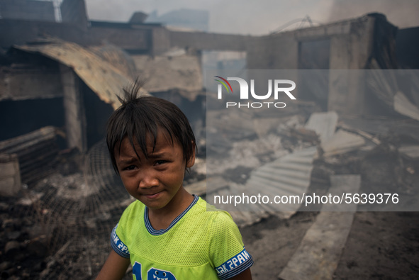 A boy walks past several houses destroyed after a fire broke out in a slum area in Tondo, Manila in the Philippines on April 18, 2020. About...
