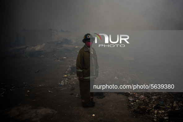 A firefighter stands at the scene of fire in a slum area in Tondo, Manila in the Philippines on April 18, 2020. About 500 families lost thei...