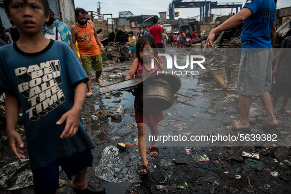 A girl carries fire debris to be sold in junk shops after a fire  broke out in a slum area in Tondo, Manila in the Philippines on April 18,...