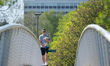 A man takes his small dog for a walk on a bridge in Peel Park, Salford, Greater Manchester...