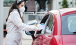 An agent with a protective suit hands a health information leaflet and an approved face ma...