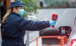 A security agent  scans the body temperature of an employee of Italian automobile manufact...