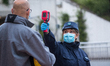  A security agent  scans the body temperature of an employee of Italian automobile manufac...