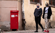A couple in protective face masks is seen walking in front of of Polish Post mail box duri...