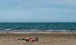 People lying on the sand at the public beach of Lido di Venezia. The permission to go to t...
