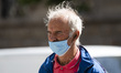 An old man with mask walks through the city during the life normalization after the Corona...