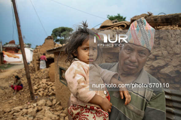 Bramha is holding his daughter in front of his destroyed house. Kabrepalan Chowk, Nepal. May 6, 2015 