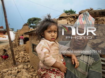 Bramha is holding his daughter in front of his destroyed house. Kabrepalan Chowk, Nepal. May 6, 2015 (
