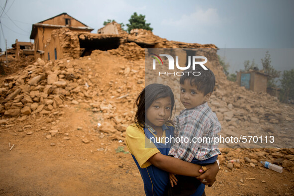 A little girl is holding her brother in front of their destroyed house. Kabrepalan Chowk, Nepal. May 6, 2015 