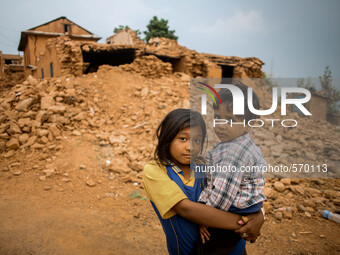 A little girl is holding her brother in front of their destroyed house. Kabrepalan Chowk, Nepal. May 6, 2015 (