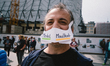 Aprotester wears a sign '' Merkel Muzzled'' during the rally against coronavirus policy in...