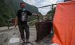 A man is pictured as he's standing near is temporary tents where 20 peoples live inside si...