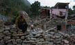 A man is pictured as he collect entire brick in order to build his house behind him on the...