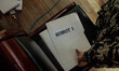 A teacher reaches for a folder containing the list of students at a cyber graduation cerem...