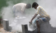 Workers cut stone during re-construction of the Raja Gopuram tower of the Arul Eswari Muth...