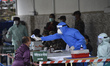 A Nepalese Army Health personnel checks the body temperature of a Nepalese people arrive f...