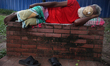 A homeless man covers his face with a mask as he sleeps on a park bench in Dhaka, Banglade...