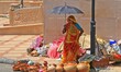 A woman vendor using umbrella from protect herself as she waiting for customer to sell  ea...