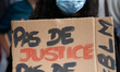 A woman holds a placard reading 'No Justice, No Peace'. Several organizations and collecti...