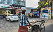 Man pushes a cart serving as a ironing board as he walks along the road with a coal powere...