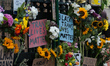 Flowers and placards are left attached to the railings at Westminster tube station after t...