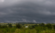 A view of a dark sky and green fields near Skala during rainy weather. The month of June...