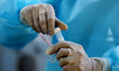 A Healthcare worker in PPE kit prepares a swab sample to be tested for COVID-19 (coronavir...