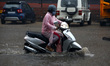 Indian People drives through a flooded road during a Heavy Monsoon Rain shower in Ajmer, R...
