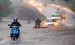 Indian People drives through a flooded road during a Heavy Monsoon Rain shower in Ajmer, R...